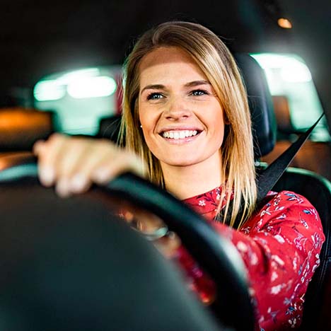 Mujer sonriente conduciendo un vehículo.